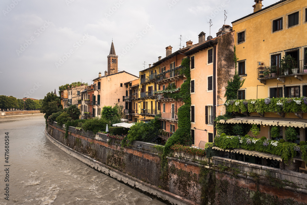Colorful facades of the old town buildings by the Adige river from the stone bridge on a cloudy day, Verona, Veneto Region, Italy