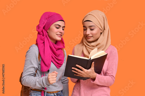 Tableau sur toile two young muslim women wearing hijab and reading book indian pakistani model
