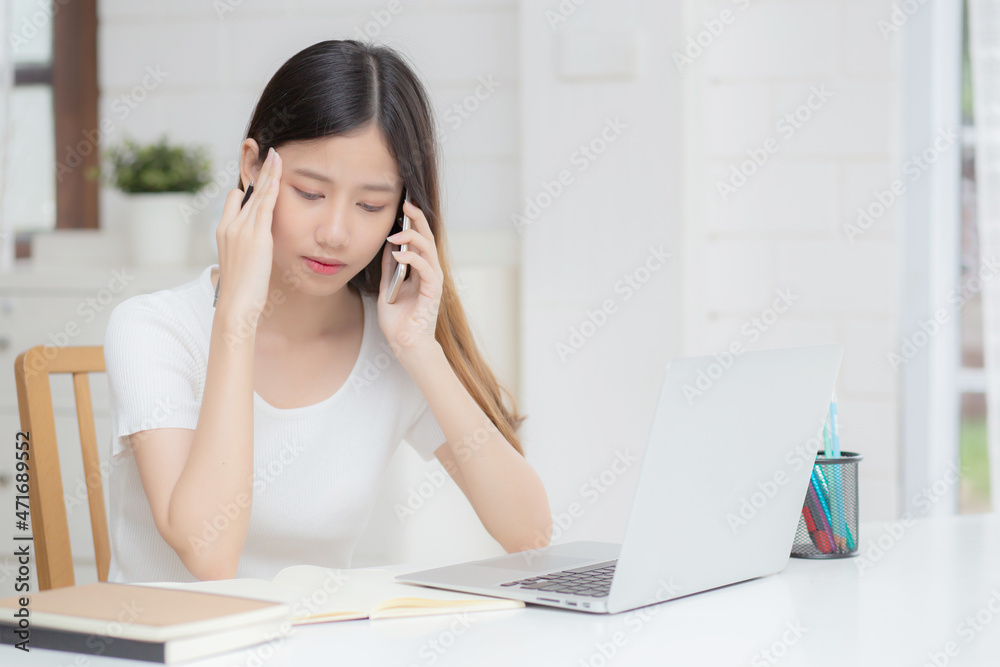 Young asian woman working on laptop computer and talking smartphone having stress and upset at home, girl having problem and worried, frustrated and unhappy, business and communication concept. Young asian woman working on laptop computer and talking smartphone having stress and upset at home, girl having problem and worried, frustrated and unhappy, business and communication concept.