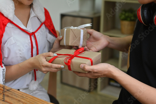 Fotografija Photo of a lovely couple giving each other Christmas presents box in the comfortable living room