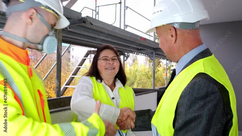 Two men, an architect and construction engineer, foreman and one woman inspect the performance of project, a construction site of a multi-storey house, building in progress Two men, an architect and construction engineer, foreman and one woman inspect the performance of project, a construction site of a multi-storey house, building in progress