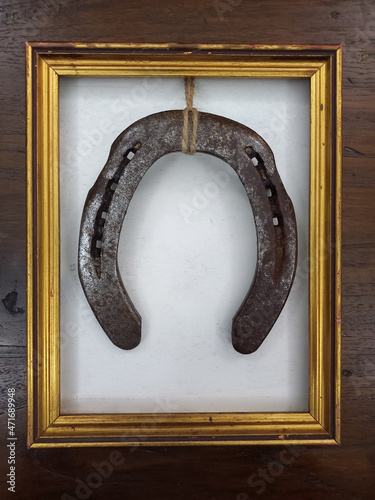 Ferro di cavallo arrugginito, incorniciato in una cornice antica dorata, regalo come portafortuna photo