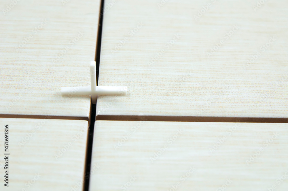 Obraz premium one white cross in the joints of tile tiles, the concept of tile laying repair