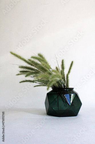 Dry herb in a dark green glass vase