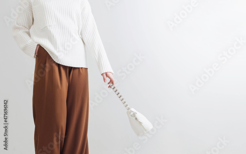 modern girl in white sweater and brown pants in white room