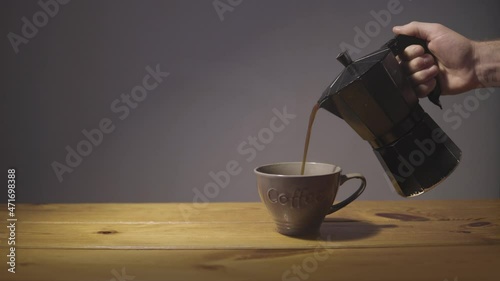 Cinemagraph of barista pouring coffee into a porcelain cup with space for graphics. Infinite loop of an espresso machine in gif 4k. Neutral background and wooden table.