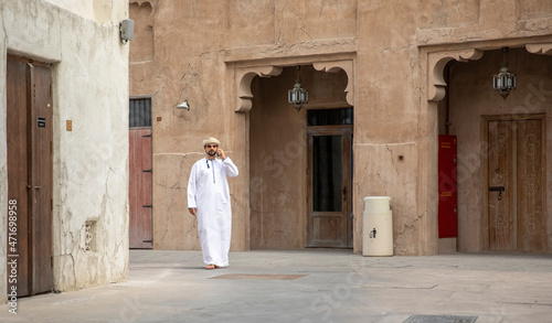 Canvas Print Arab Man walking in al seef district in dubai and talking in the phone