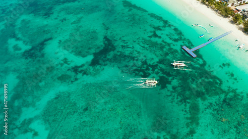 Tourist boats on the surface of the turquoise lagoon, aerial view. Seascape with beach on tropical island. Summer and travel vacation concept. Boracay Island, Philippines