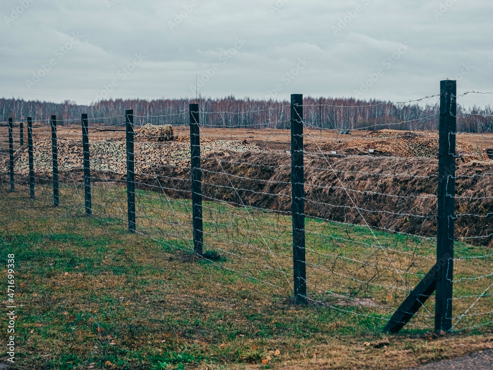 Rows of barbed wire on the state border. The separation of the two countries. Foggy autumn landscape 