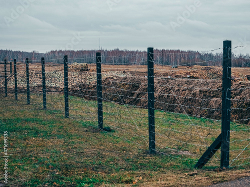 Rows of barbed wire on the state border. The separation of the two countries. Foggy autumn landscape 