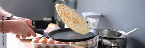 Fotografiet Male chef tossing pancake in frying pan in kitchen closeup