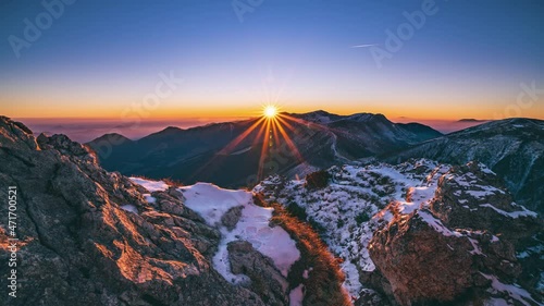 Beautiful sunbeam light of sun at sunrise in alps mountains landscape in autumn morning nature with first snow on rocky peak Time lapse