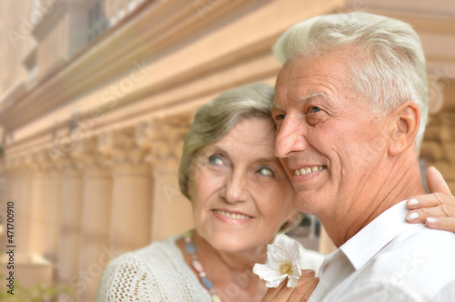 Portrait of happy senior couple posing against blurred cityscape background