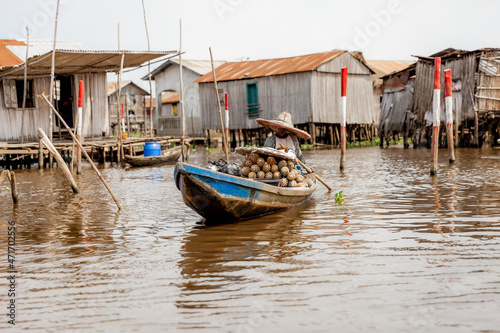 Woman rowing in Ganvié, Benin on Lake Nokoue. She has a large load of pineapples she's going to sell at the market.