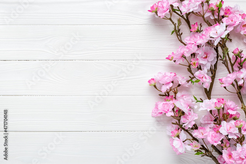 Sakura branches on a wood table. Pink cherry blossom on white wooden background. Frame border. Template with copy space. Pattern with place for text. Spring mockup. Greeting card, layout.