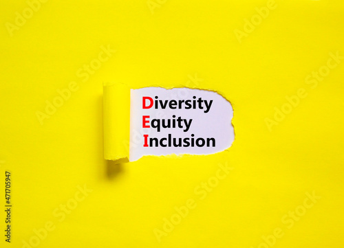 Diversity, equity, inclusion DEI symbol. Words DEI, diversity, equity, inclusion appearing behind torn yellow paper. Pink background. Business, diversity, equity, inclusion concept, copy space.