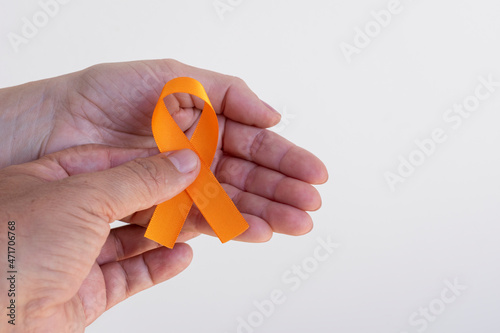 man handing orange ribbon to woman. campaign to prevent skin cancer, melanoma, December orange
