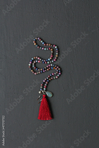 Rosary mala 108 beads from natural stones tourmaline lie on black modern background. Author's jewelry from natural stones, Buddhism, mantra, prayer, rosary from stones for prayer, beauty. Long beads photo