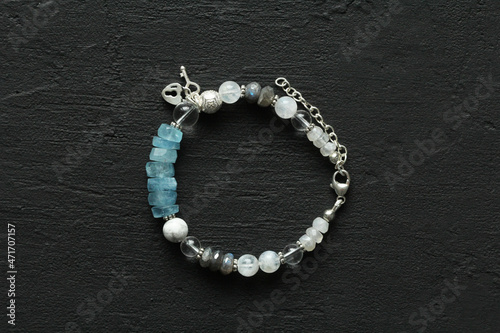 Beautiful asymmetrical designer bracelet made of natural stones and silver. Aquamarine, rock crystal, cacholong, larimar, moonstone. Handmade jewelry made from natural stones on black background photo