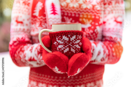 Girl wearing sweater and gloves with Christmas ornament holding the cup