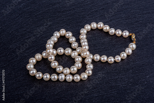 A necklace of pearl beads on a stone surface.