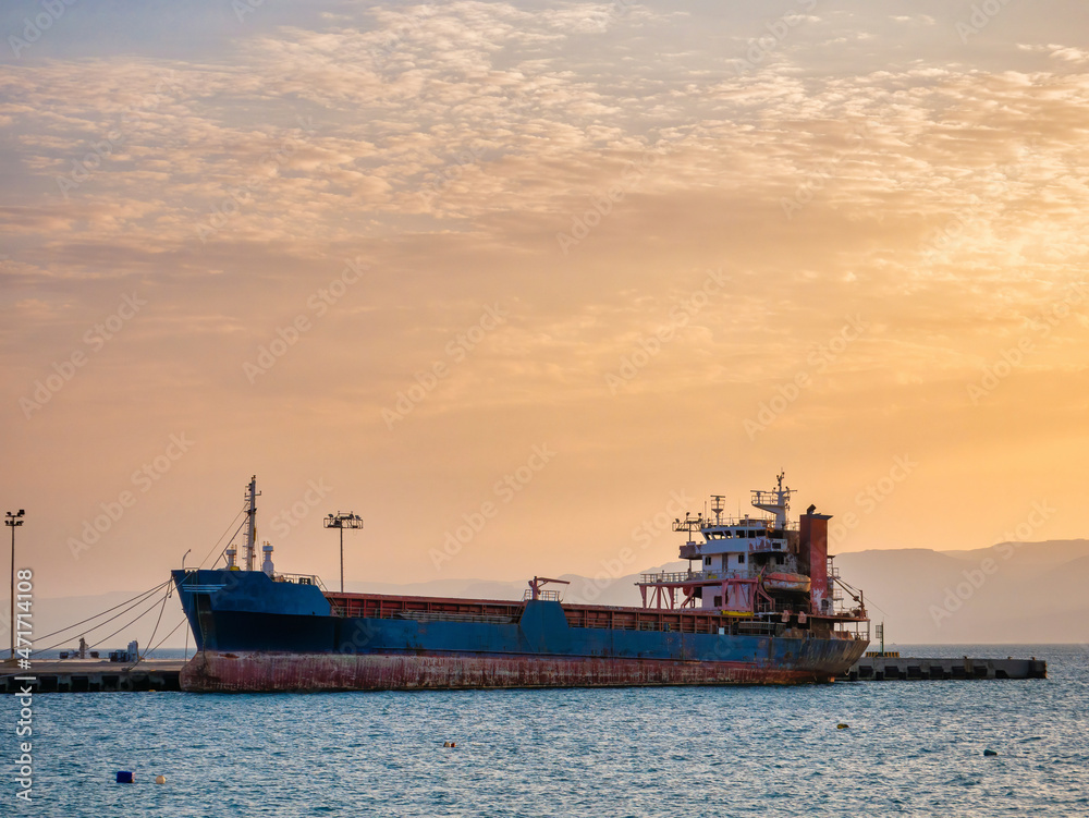 Scenic view at sunset with a docked old rusted ship in the port of Aqaba city, Jordan. Scenic view at sunset with a docked old rusted ship in the port of Aqaba city, Jordan.