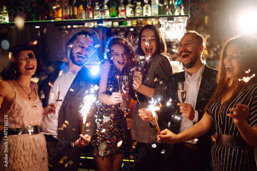 Photography Young  friends celebrate new year and holding bengal lights and glasses with drink