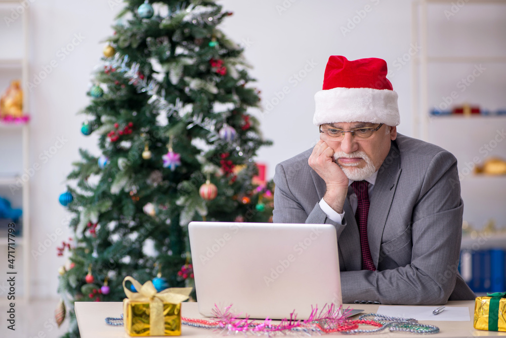 Aged male employee celebrating Christmas at workplace Aged male employee celebrating Christmas at workplace