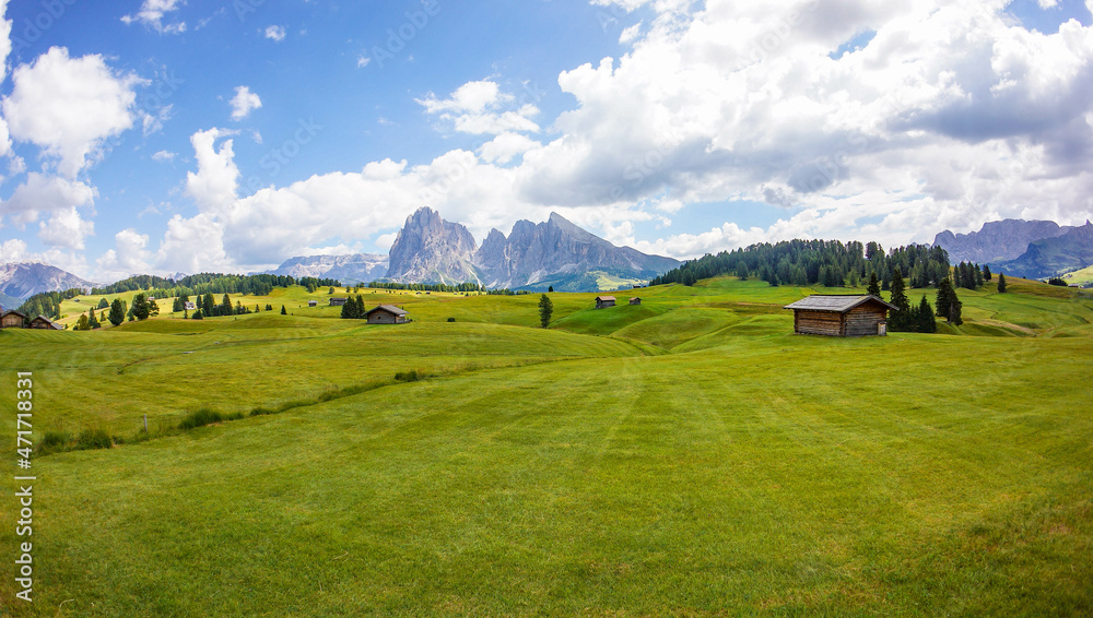 Obraz premium Dolomites, Italy, August 2018, green and yellow Alpe di Siusi valley with a small house in the background of mountains