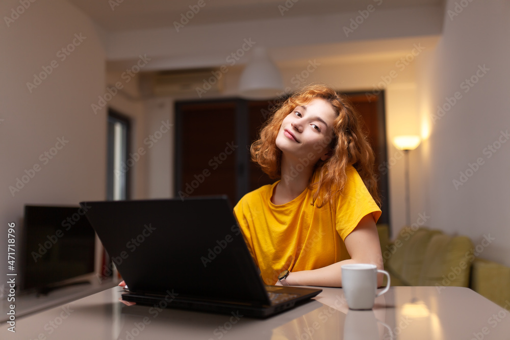 Fototapeta premium Cute girl working on a computer in living room. Student taking online course. Home education concept