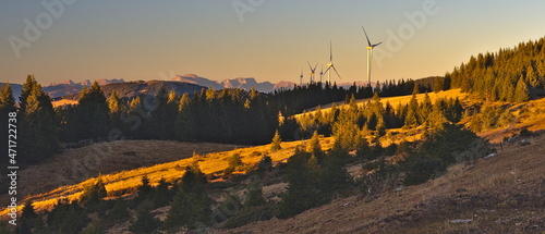 Panorama of wind turbines in mountains. Windmills at Sunset against orange sky in Austria.