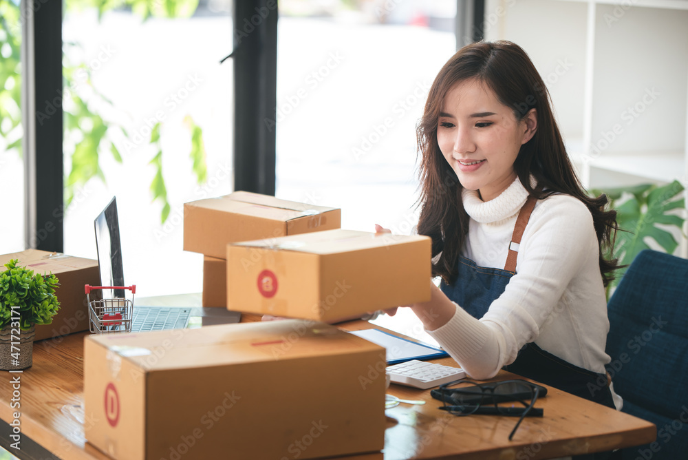 Small start-up business owners using computers at work, freelancers, saleswoman, checking production orders. Pack products for delivery to customers Small start-up business owners using computers at work, freelancers, saleswoman, checking production orders. Pack products for delivery to customers