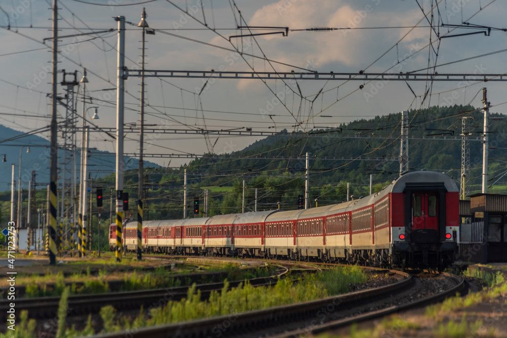 Passenger train with red electric locomotive and passenger coaches in summer Passenger train with red electric locomotive and passenger coaches in summer