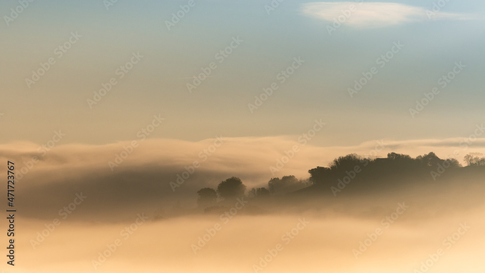 hilly mountain landscape with fog at dawn