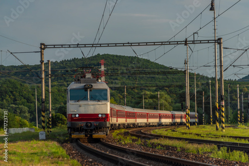 Passenger train with red electric locomotive and passenger coaches in summer