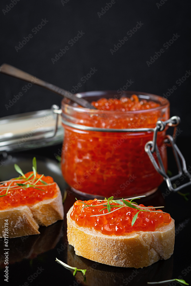 Delicious fresh red caviar with baguette toasts on dark background Delicious fresh red caviar with baguette toasts on dark background