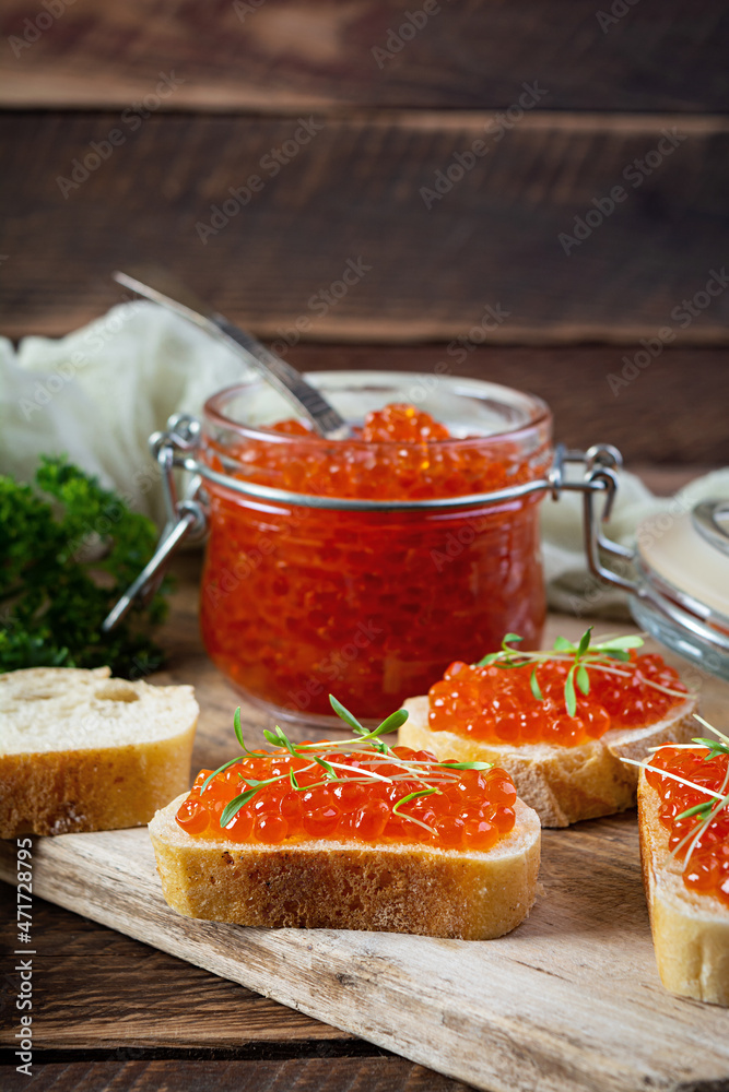 Delicious fresh red caviar with baguette toasts on wooden background Delicious fresh red caviar with baguette toasts on wooden background