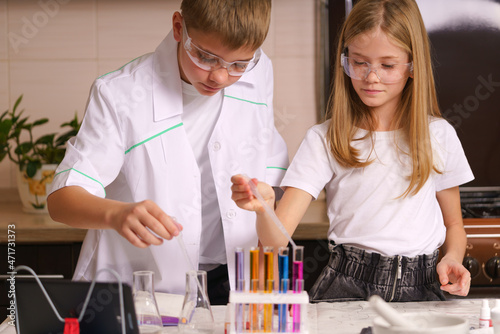 a boy and a girl are having a chemistry lesson at home. The laboratory is at home. Chemistry lesson in the kitchen. Online education. Home schooling.