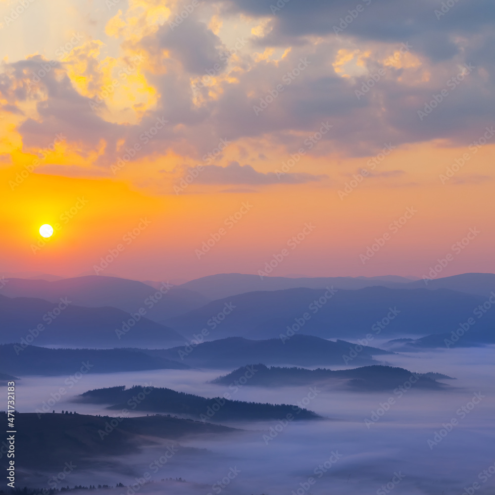 mountain ridge silhouette in blue mist at the sunrise, early morning mountain valley scene