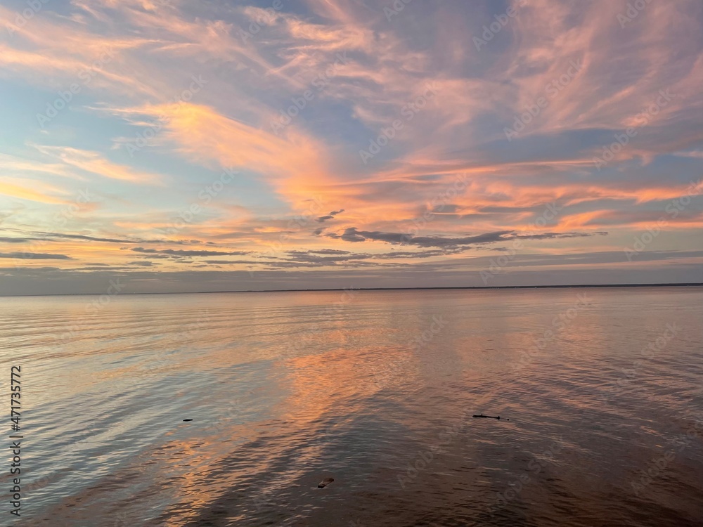 colorful sunset clouds reflecting onto calm bay water 