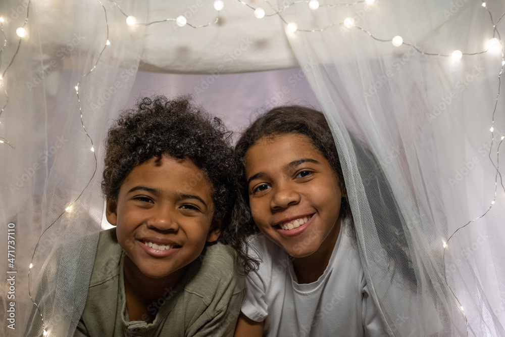 Φωτογραφία Portrait of happy African American siblings lying inside of handmade tent decora