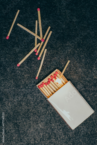 Matches in a box, dark background. burning match. Close-up shot. Matches in an open box of matches on a fabric felt backing. matches on a black background.scattered matches next to the box