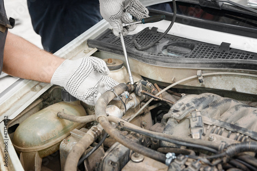 Mechanic repairing engine on a car using wrench. Close up of hands