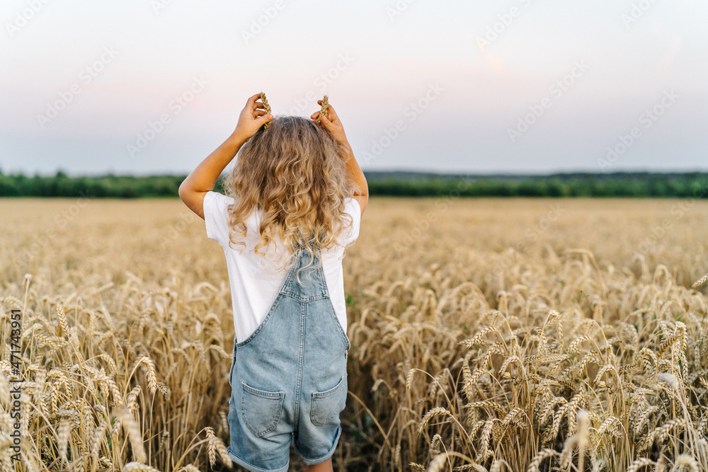 a little blonde curly girl running in a wheat field, the concept of human freedom, people from behind a little blonde curly girl running in a wheat field, the concept of human freedom, people from behind