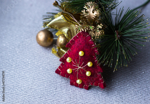 Christmas background, copy space. New Year's composition of a toy red Christmas tree with golden beads and a Christmas branch on a light background. Happy New Year concept. Christmas decoration. 