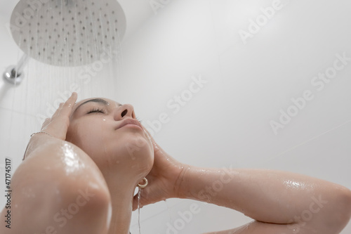 Tableau sur toile Mujer joven de pelo negro en la ducha con el agua cayendo sobre su cara en primer plano