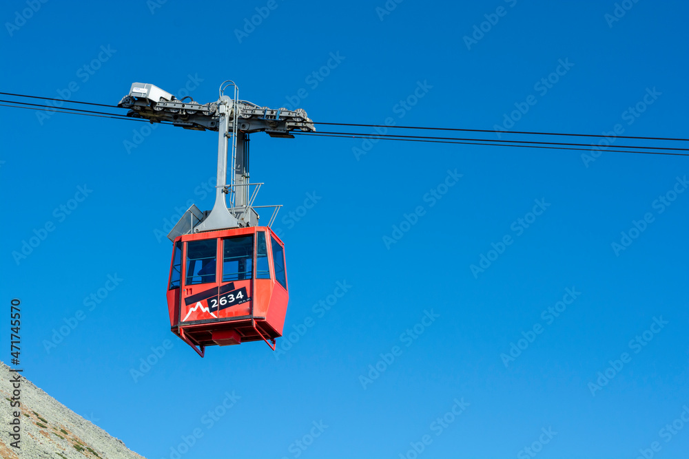 A red cable car on its way from Skalnate pleso to Lomnicky peak. Red gondola moving up to Lomnica peak in High Tatras Mountains. Slovakia.