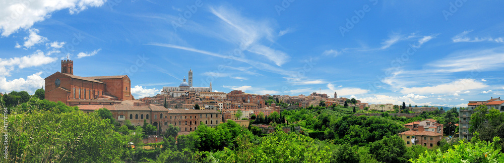 Cityscape Of Siena In Tuscany Italy With The Famous Cathedral And San Domenica Church On A Beautiful Spring Day With A Blue Sky And A Few Clouds
