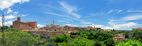 Cityscape Of Siena In Tuscany Italy With The Famous Cathedral And San Domenica Church On A Beautiful Spring Day With A Blue Sky And A Few Clouds