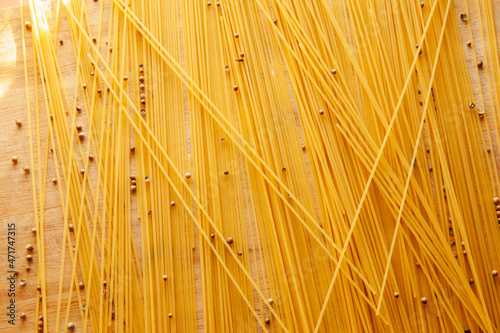 Spaghetti scattered on the table with black pepper peas. Italian food concept. Spaghetti background for post, screensaver, wallpaper, postcard, poster, banner, cover, header for website. Food photo © vveronka